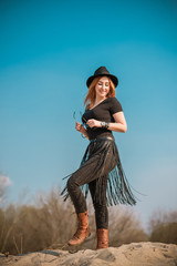 Fashionable outfit of redhead woman in jeans with fringe belt and Fedora hat
