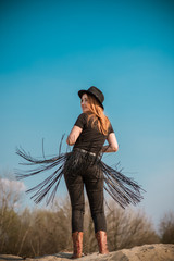 Fashionable outfit of redhead woman in jeans with fringe belt and Fedora hat