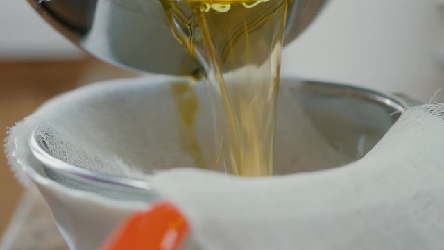 Close-up of straining melted butter through a gauze. Cooking ghee oil