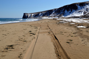 Tire marks on the sand of a deserted beach on a spring day