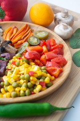 Nutritious and healthy buddha fajita bowl with sweet corn, green peas, red bell pepper, jalapenos, carrots, mushrooms, spinach, beetroot and sweet potatoes surrounded by ingredients and lemon
