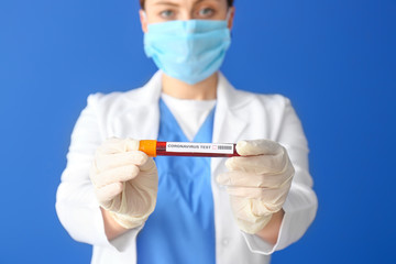 Doctor with blood sample on color background. Concept of Coronavirus epidemic