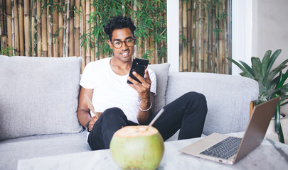 Young man using smartphone sitting on sofa