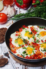 Shakshouka with five cooked eggs on top of tomato sauce in cast iron skillet