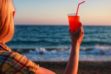 Woman holding fresh fruit cocktail on a tropical island beach