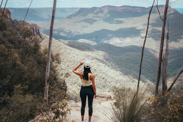 Woman hiking Blue Mountains Australia. Dramatic views of valley, landscape, green rainforest jungle. Adventure, freedom, fun concepts. Tourist mountain trek. Shot in Sydney, NSW.