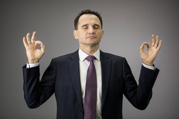 Handsome middle age businessman relaxing and meditation, deals with emotional angry customer, stress management concept, try to calm down during financial problems and economic crisis due to covid-19