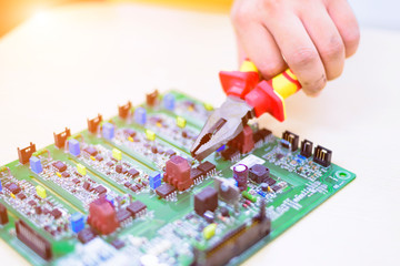 Use motherboard repair tools, Repair electrical circuits on the table and soft light, Electronic cards are placed on the table with instruments and red pliers.