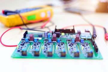 Motherboard electronic components and a yellow multimeter mounted on the back and soft light.