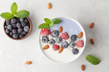 Healthy Breakfast smoothie bowl with blue matcha tea, coconut, yogurt, frozen berries, nuts and topped with mint. Vegan food