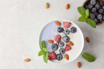Healthy Breakfast smoothie bowl with blue matcha tea, coconut, yogurt, frozen berries, nuts and topped with mint. Vegan food