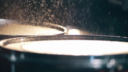 A musician hits wet cymbals.