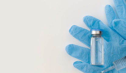 Banner with top view of medicine bottle, blue rubber gloves, syringes on grey background. Coronavirus vaccine development. 2019-nCoV liquid drug, virus antidote. Copy space. Health care concept.