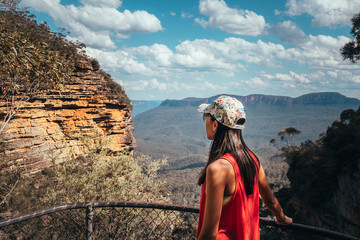 Woman hiking Blue Mountains Australia. Dramatic views of valley, landscape, green rainforest jungle. Adventure, freedom, fun concepts. Tourist mountain trek. Shot in Sydney, NSW.