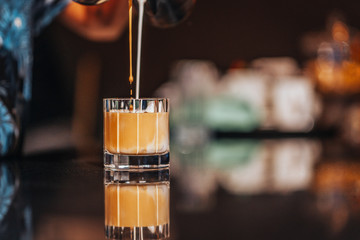 Iced americano preparation, pouring milk and coffee into iced glass
