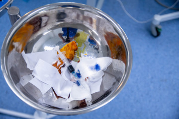 Surgical trash bin in the operating room with used bandage and syringe.