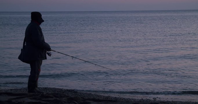 Side view, long shot male, no face, winter lure fishing, shoreline, coast of Spain