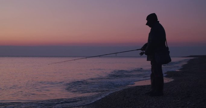 Wide shot, full body angler fishing, horizon sunrise, shoreline, Almeria, Spain