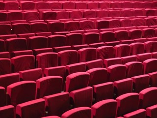 Rangées de fauteuils rouges dans une salle de spectacle vide