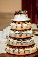 Wedding cake on a stand with individual servings with fresh fruits
