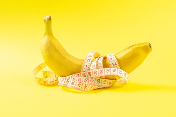 Banana with tape for measuring figure. Centimeter ruler spinned around fruit. Tape wrapped around...