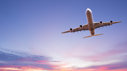 Fototapeta na wymiar Commercial airplane jetliner flying above dramatic clouds in beautiful light. Travel concept.