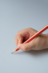 Hand of an Asian child holding a pencil and writing something
