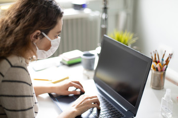 Young business woman working from home wearing protective mask