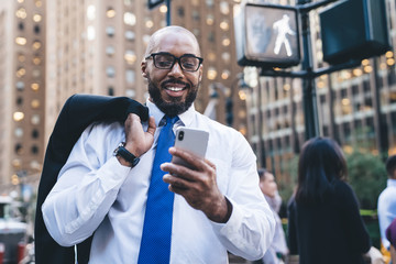 Black businessman using smartphone on street