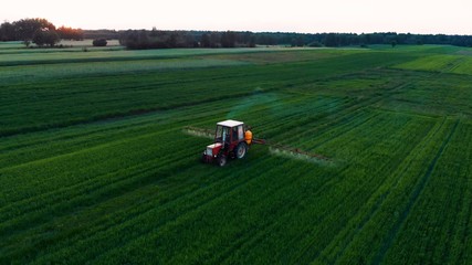 Tractor spraying the rural green field. Agriculture and farming concept. Aerial