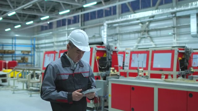 Asian, Korean chinese professional male engineer man business people in hard hat working on engineering industrial manufacturing facility using tablet indoors, worker architect inspection. slow-mo 4 K