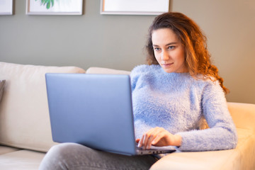 Naklejka premium Young woman using laptop on sofa