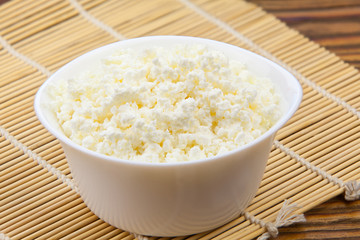 Tasty fresh grained cottage cheese on a plate on  wooden table