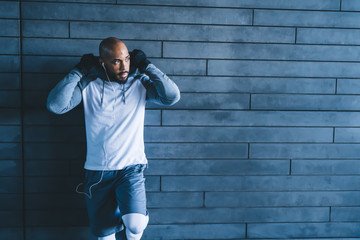 Athletic African American man looking away and leaning on wall