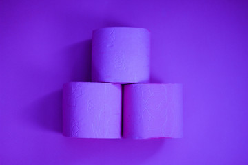 Several rolls of toilet paper isolated on lush purple background. A supply of toilet paper in case of a pandemic. COVID-19 coronavirus outbreak concept. Shortage due to buying panic. Сopy space.