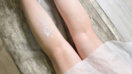 Application of talcum powder on female legs. Hair removal procedure.