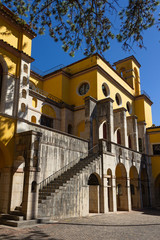 The Vittoriale degli Italiani is a monumental complex built in Gardone Riviera, on Lake Garda. The solemn architectures are painted with yellow ocher, a color that contrasts with the blue sky. Italy.