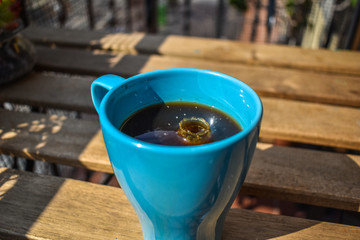 Milk drops falling into a cup of coffee on a terrace.
