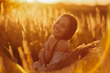 Beautiful carefree woman in fields being happy outdoors. Outdoor atmospheric lifestyle photo of young beautiful lady. Brown hair and eyes. Warm autumn. Warm spring.
