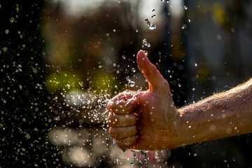 Male Fist through the Blue Water and splashing drops,Like hand sign