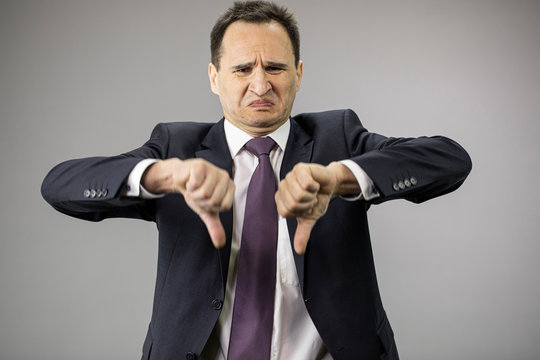 Disgusted Middle Aged Businessman In Formal Clothes, Tie Showing Dislake Signs On Isolated Gray Background With Copy Space. Portrait Of Displeased Man, Economy Problems, Taxes, Small Business Concept