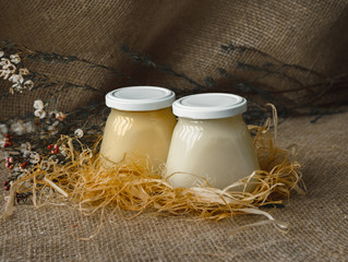 Ghee and clarified butter in jars on a straw against a matting background. Copyspace