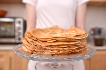 Young woman housewife holds a lot of pancakes. Quarantine household chores concept