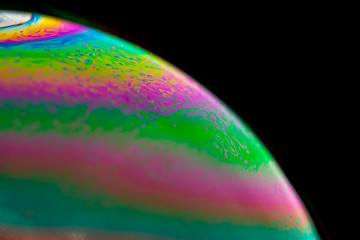 Psychedelic abstract planet from soap bubble, Light refraction on a soap bubble, Macro Close Up in soap bubble. Rainbow colors on a black background. Model of Space or planets universe cosmic galaxy.