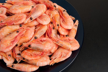 Boiled shrimp on a plate on a black background