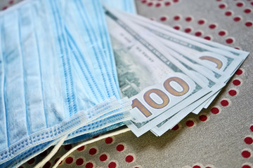 Obraz premium Medical masks with money. American dollars with protective masks. A fan of dollars with a fan of medical masks.