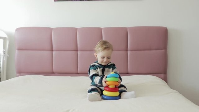 One year old baby boy have fun. Happy cute boy has fun playing colorful toy in home living room