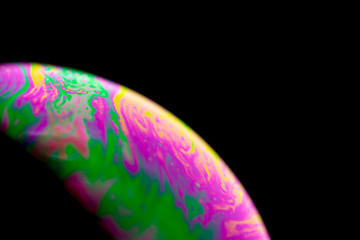 Psychedelic abstract planet from soap bubble, Light refraction on a soap bubble, Macro Close Up in soap bubble. Rainbow colors on a black background. Model of Space or planets universe cosmic galaxy.