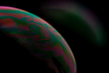 Psychedelic abstract planet from soap bubble, Light refraction on a soap bubble, Macro Close Up in soap bubble. Rainbow colors on a black background. Model of Space or planets universe cosmic galaxy.