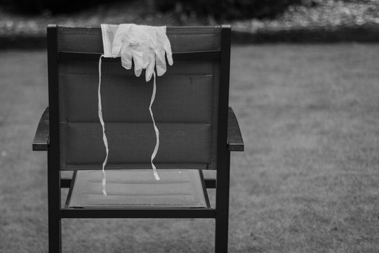 Black and white photo of a mask and rubber gloves on a chair